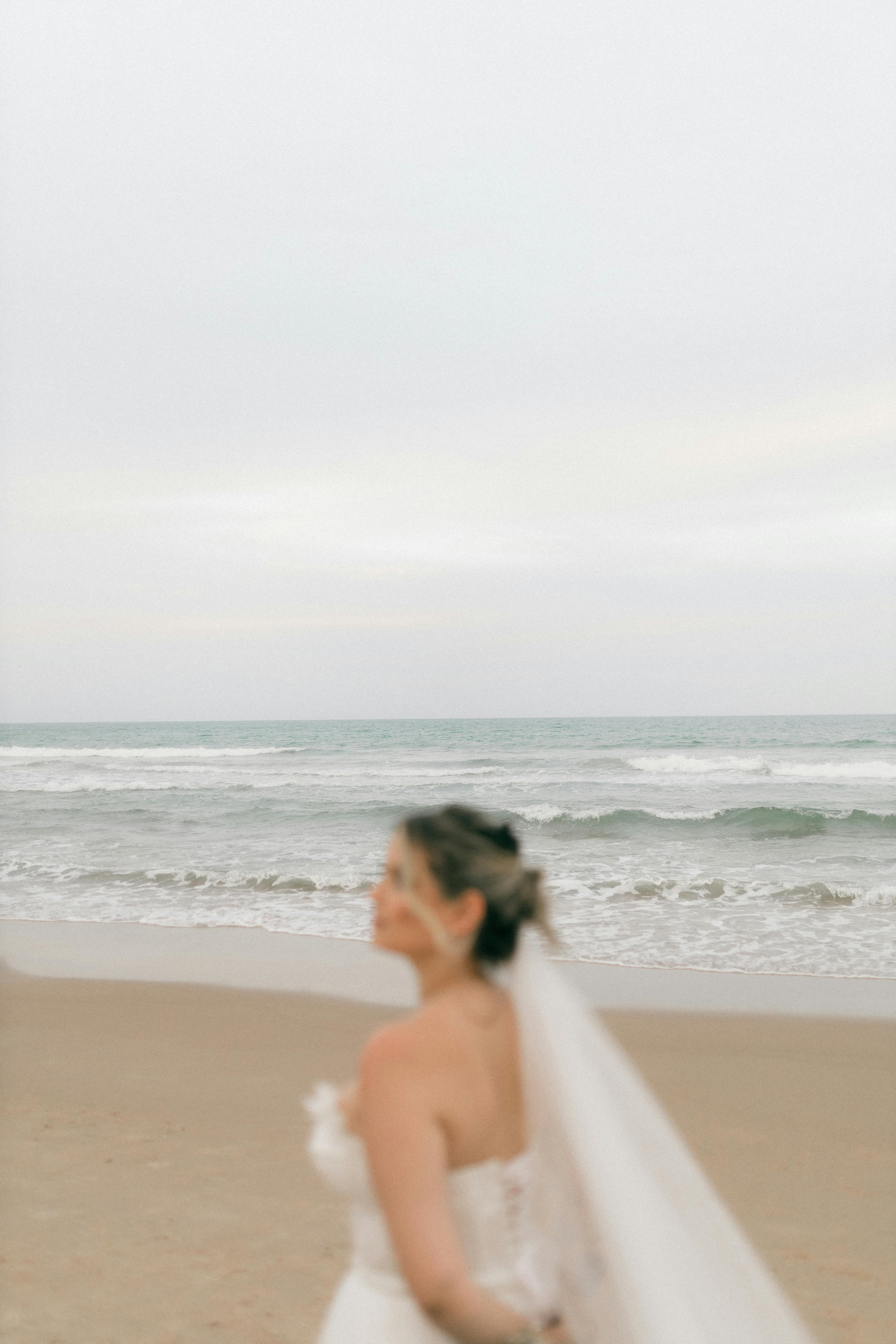 Bride on a Cyprus beach with her veil catching ocean breeze