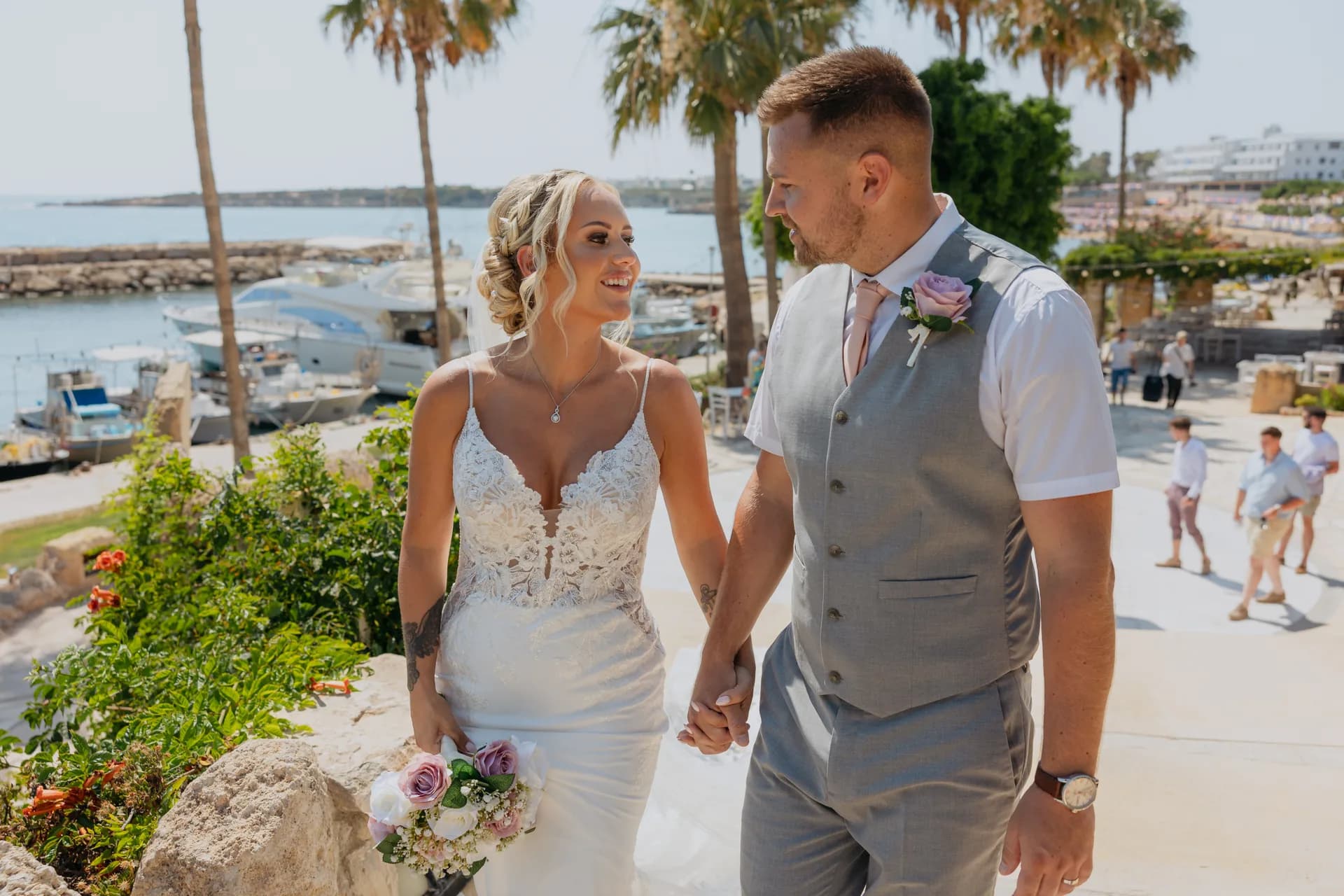 Bride and groom hand in hand above the harbour at Coral Beach, palms and turquoise bay behind