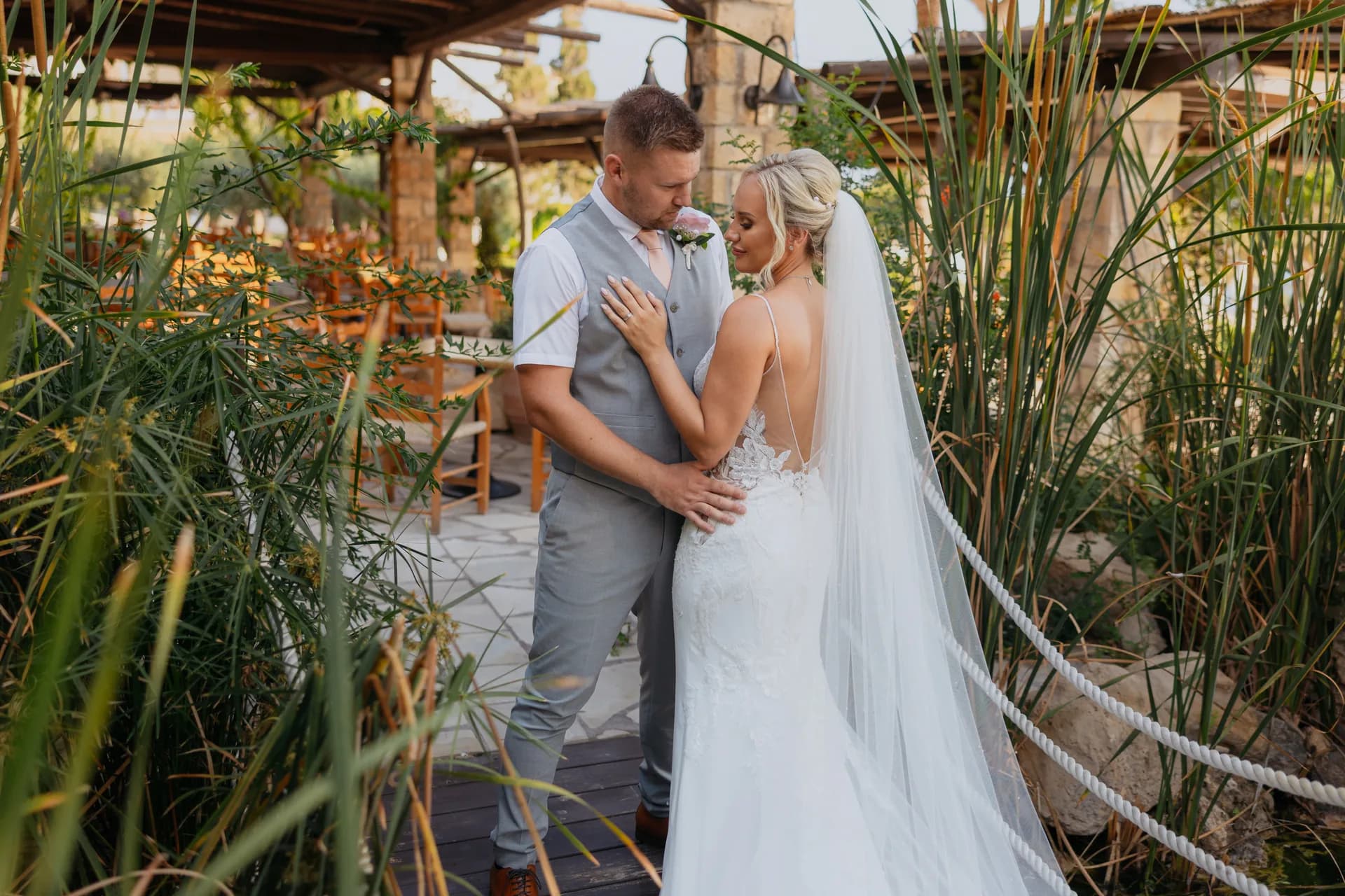 Couple on the rope bridge in the reed garden at Coral Beach, lit dining terrace behind