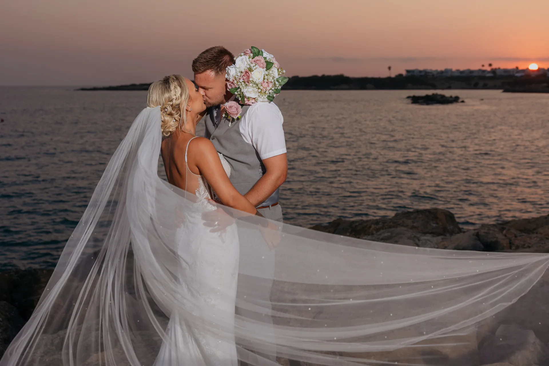 Bride and groom on the rocks at Coral Beach as the sun sets over Coral Bay