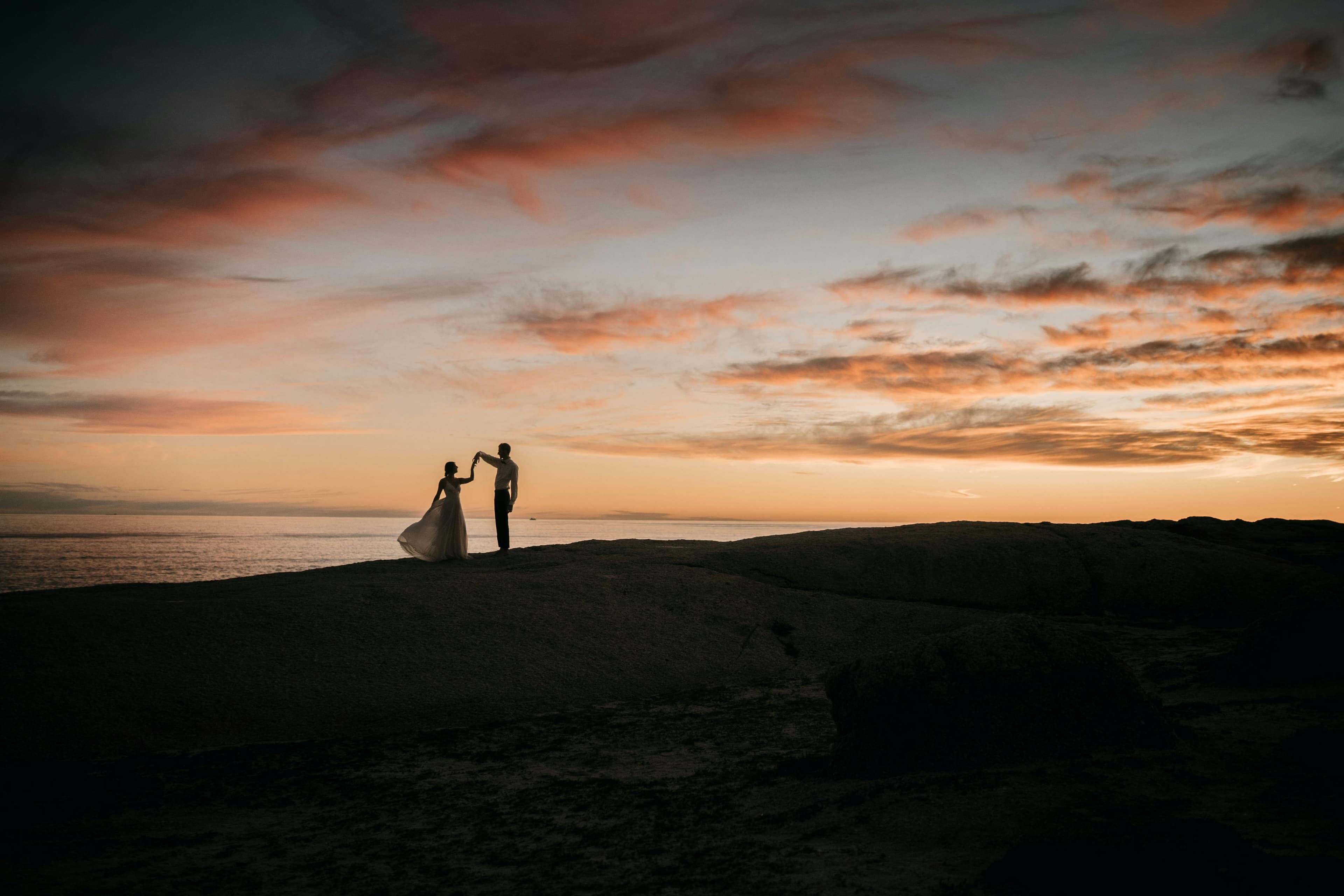 Couple silhouetted on a Cyprus clifftop at sunset