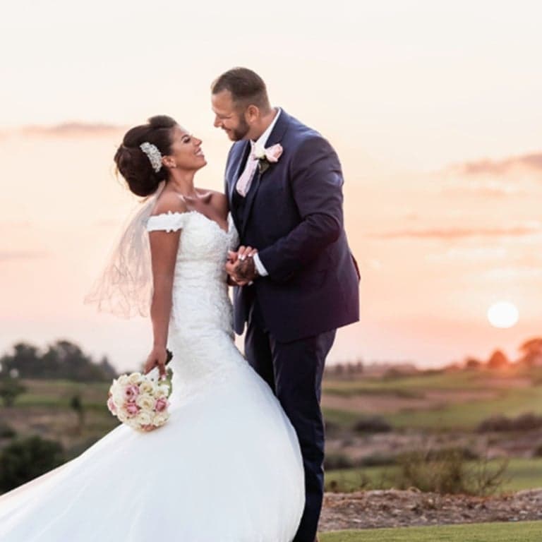 Bride and groom holding hands and looking at each other during golden hour portraits after an intimate Cyprus wedding