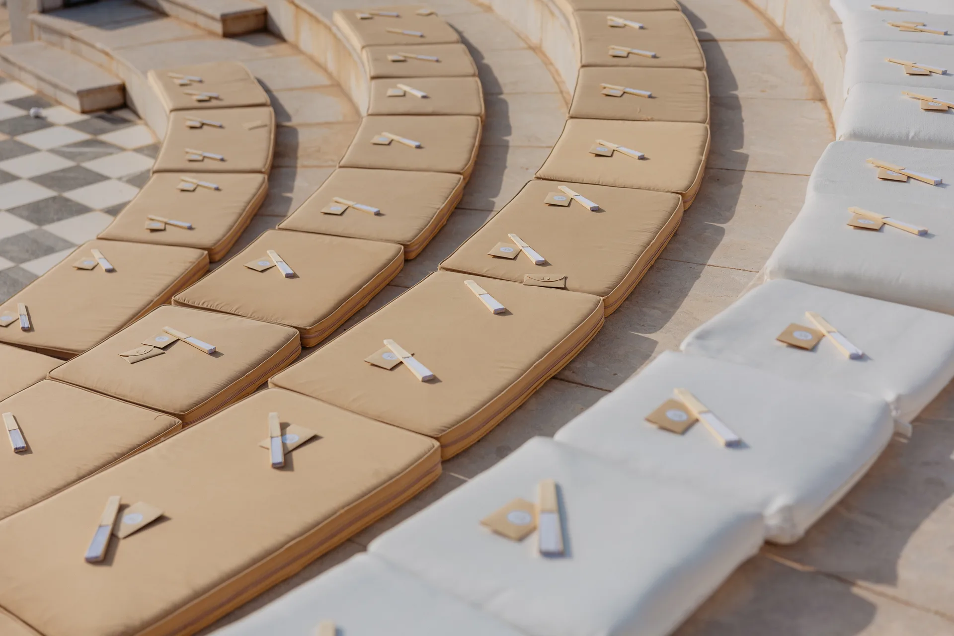 Paper fans and favour envelopes laid along the curved cushioned tiers of the Elysium’s ceremony amphitheatre