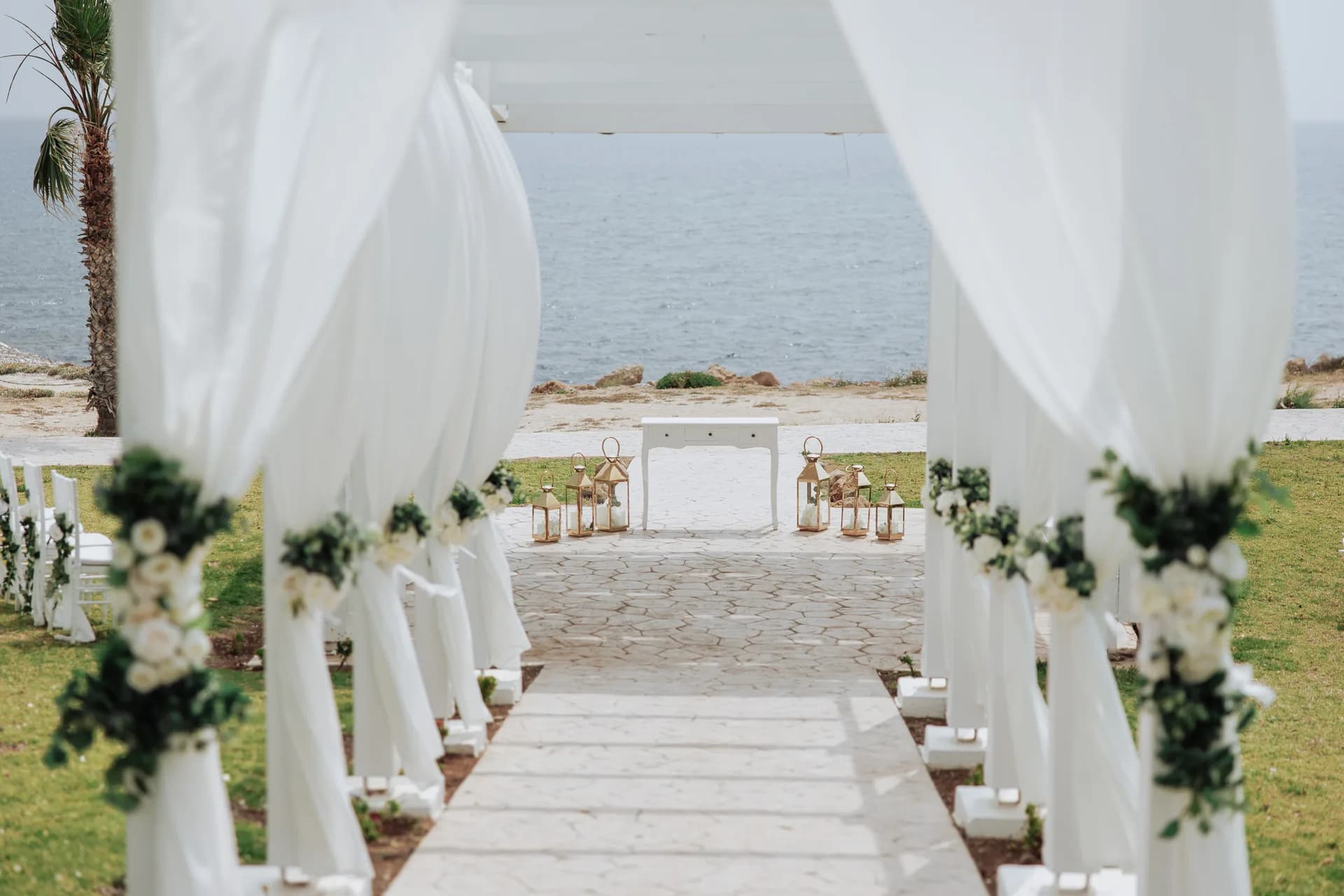 White drapes and rose swags framing King Evelthon’s flagstone ceremony aisle running down to the Mediterranean