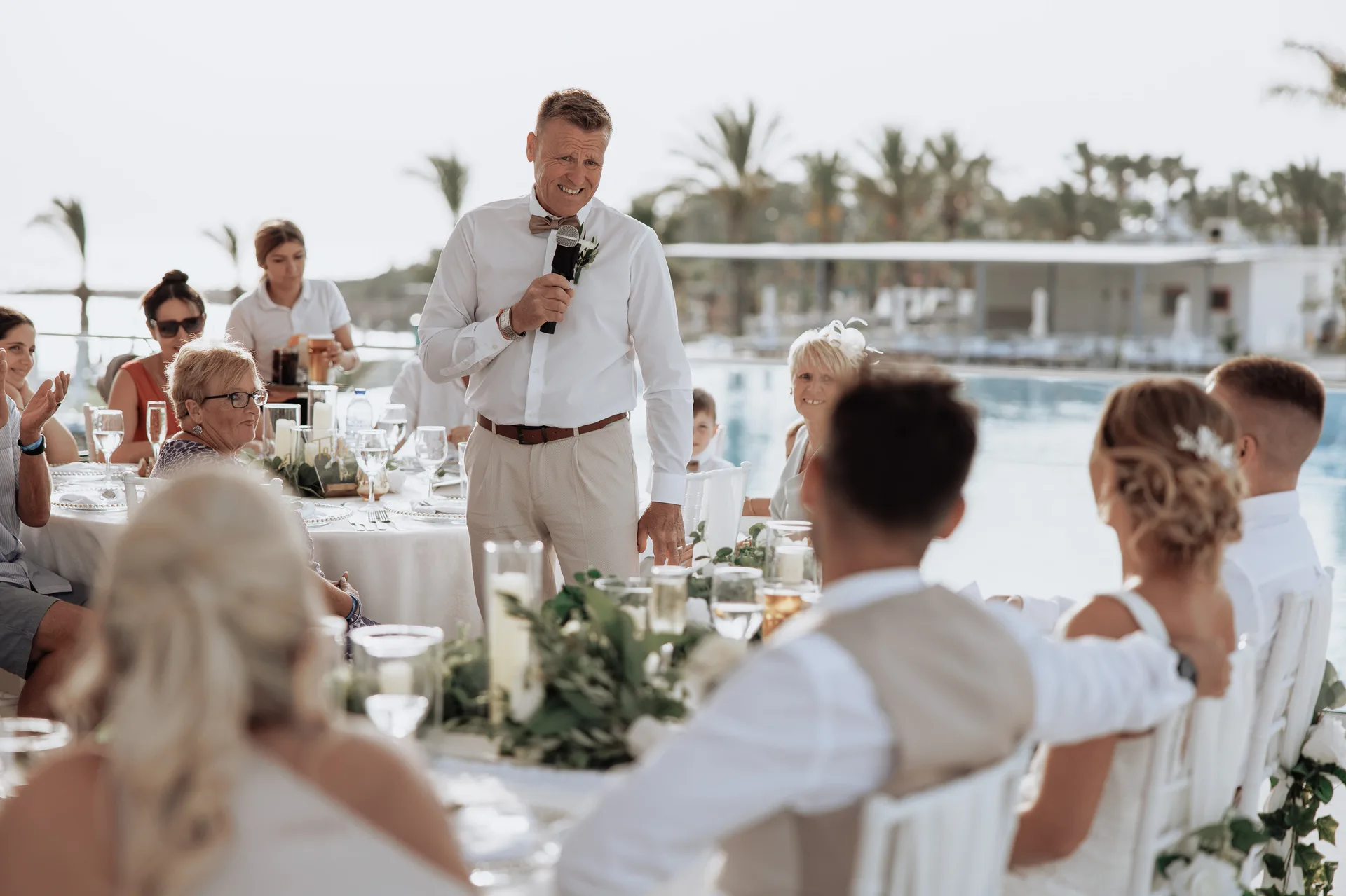 Wedding reception laid out beside the main pool at King Evelthon, palms and the resort buildings behind