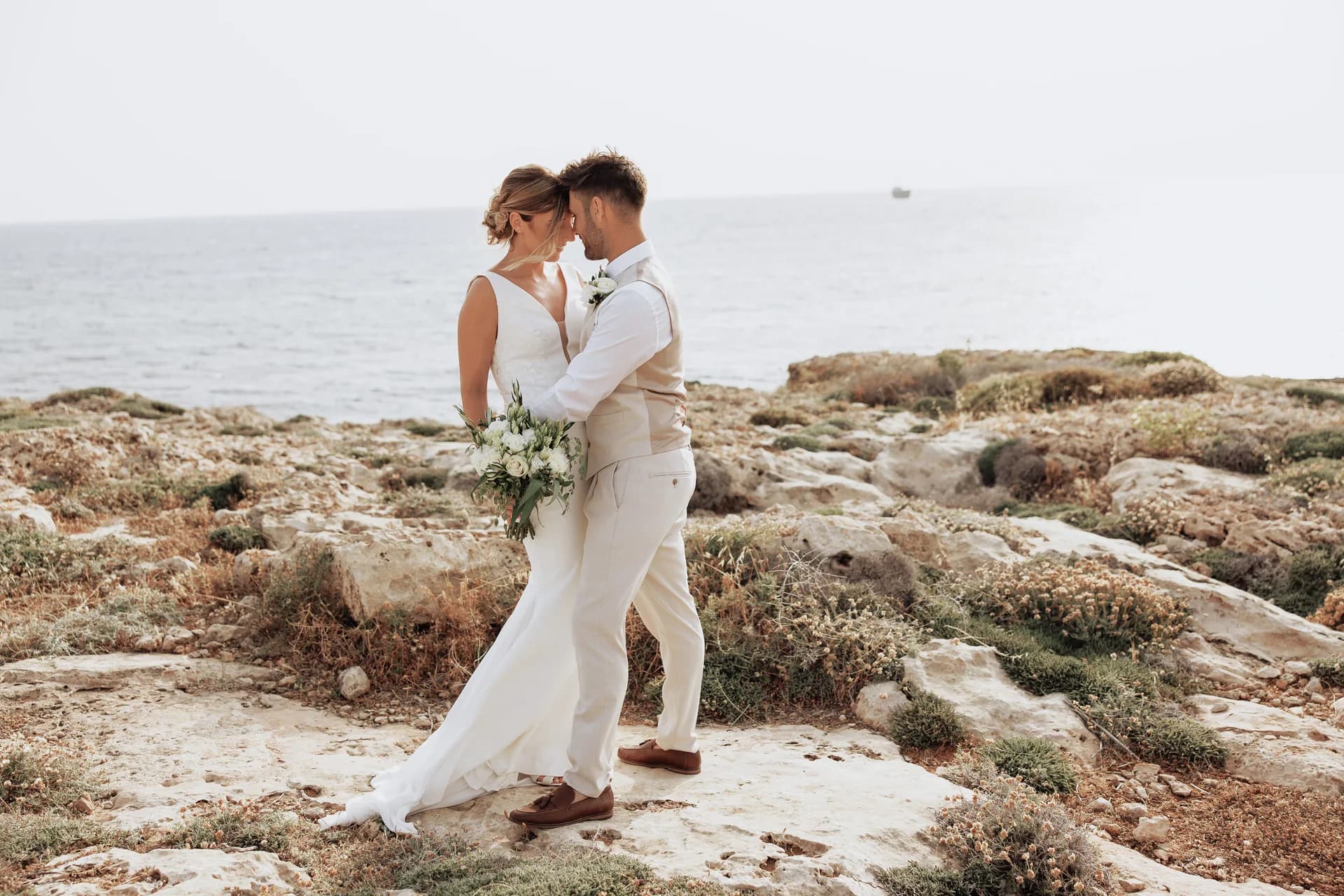 Couple on the rocky shoreline below King Evelthon, sea stretching behind