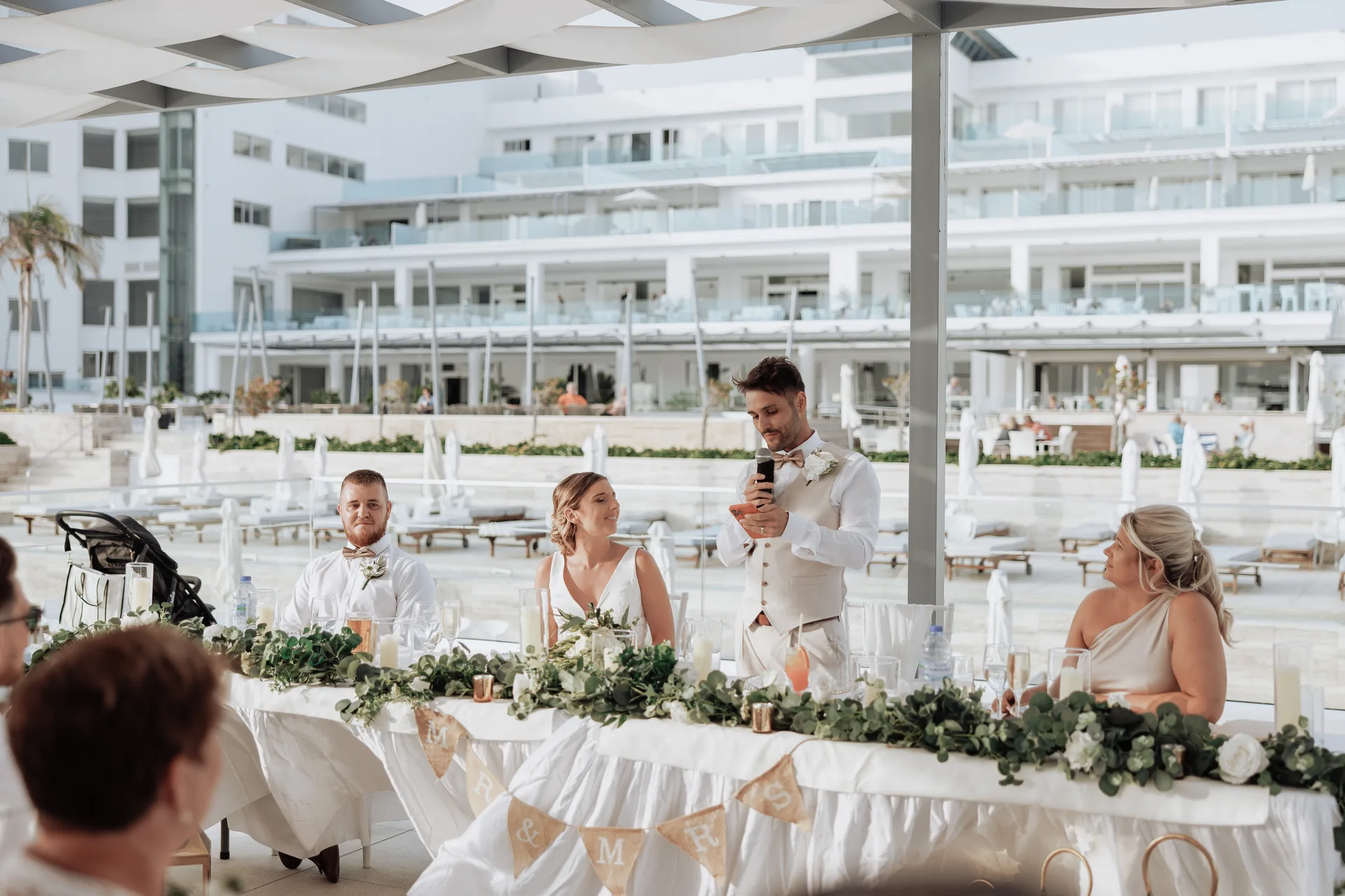 Speeches at the garland-dressed top table, King Evelthon’s white terraces behind