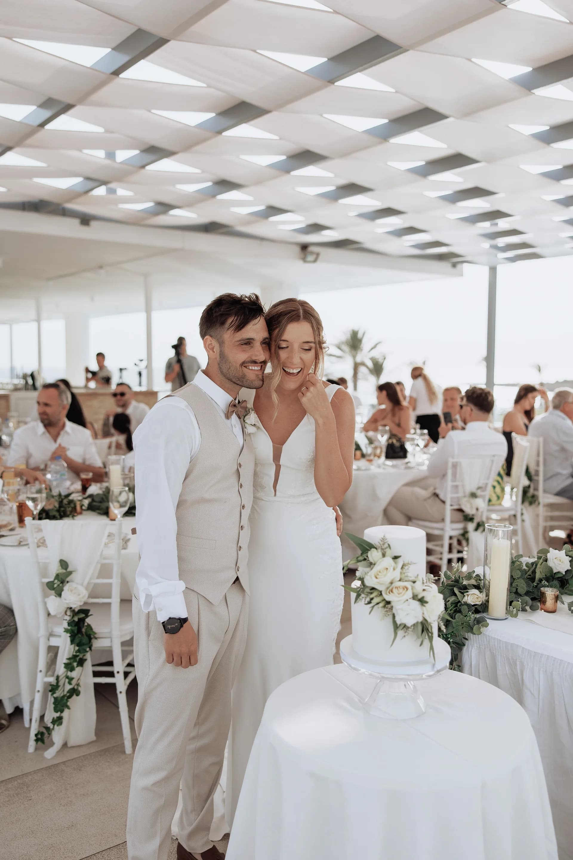 A tiered wedding cake in King Evelthon’s canopied reception pavilion, guests dining behind