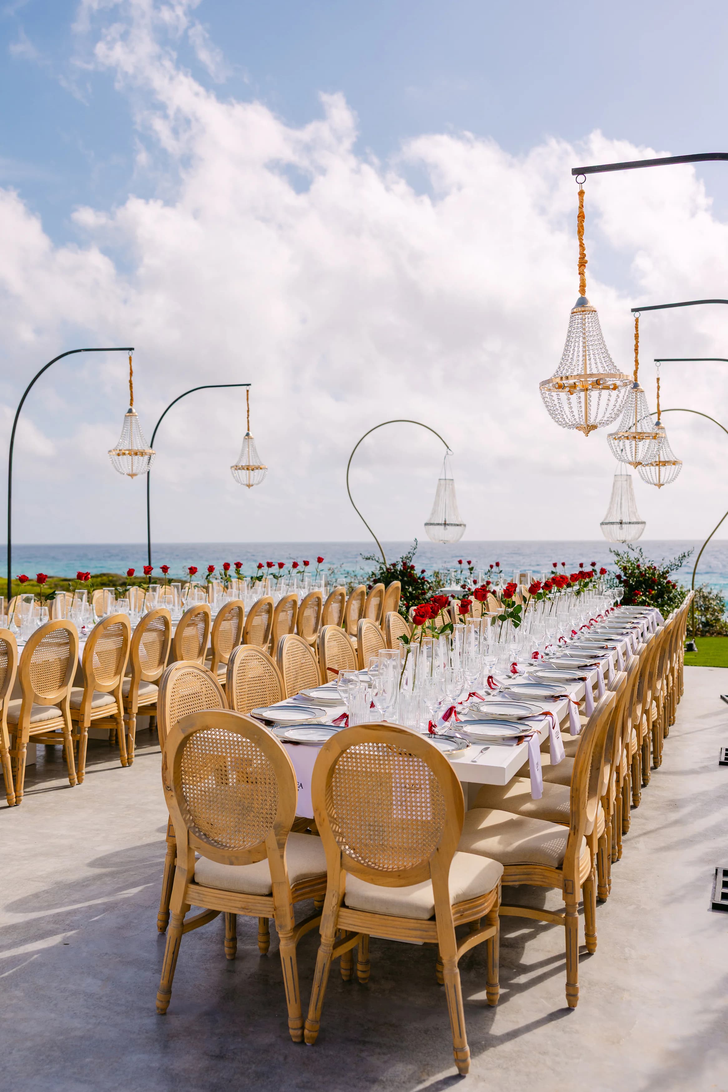 OZEA wedding banquet table from the end with crystal chandeliers, gold arches and the Mediterranean Sea on the horizon