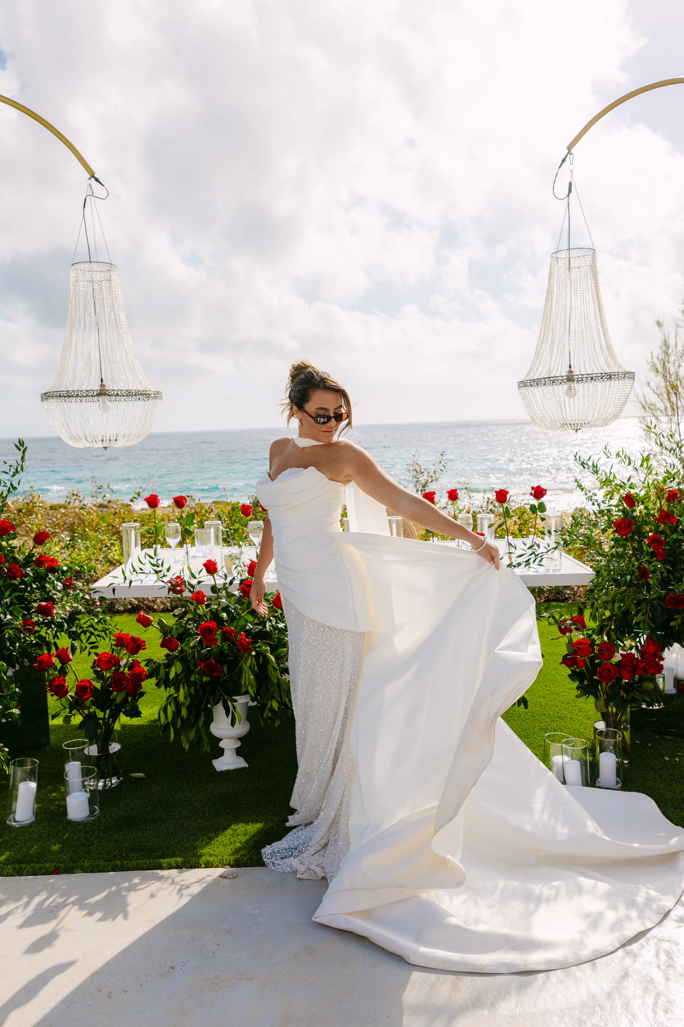 Bride twirling her gown between crystal chandeliers and red rose arrangements at OZEA, Sea Caves Paphos