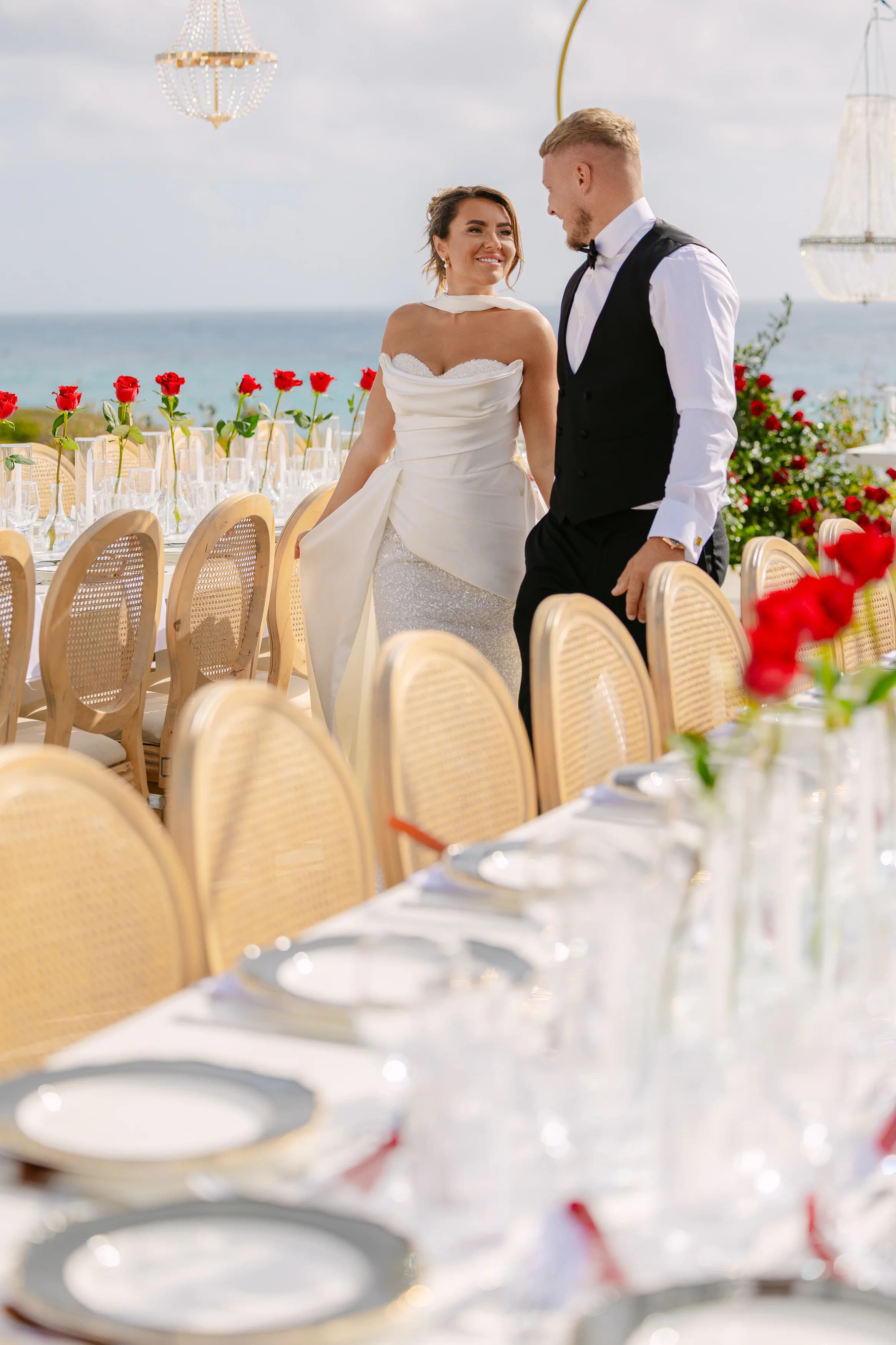 Bride in a second mermaid-style wedding dress with detachable train standing beside the groom at the OZEA reception table
