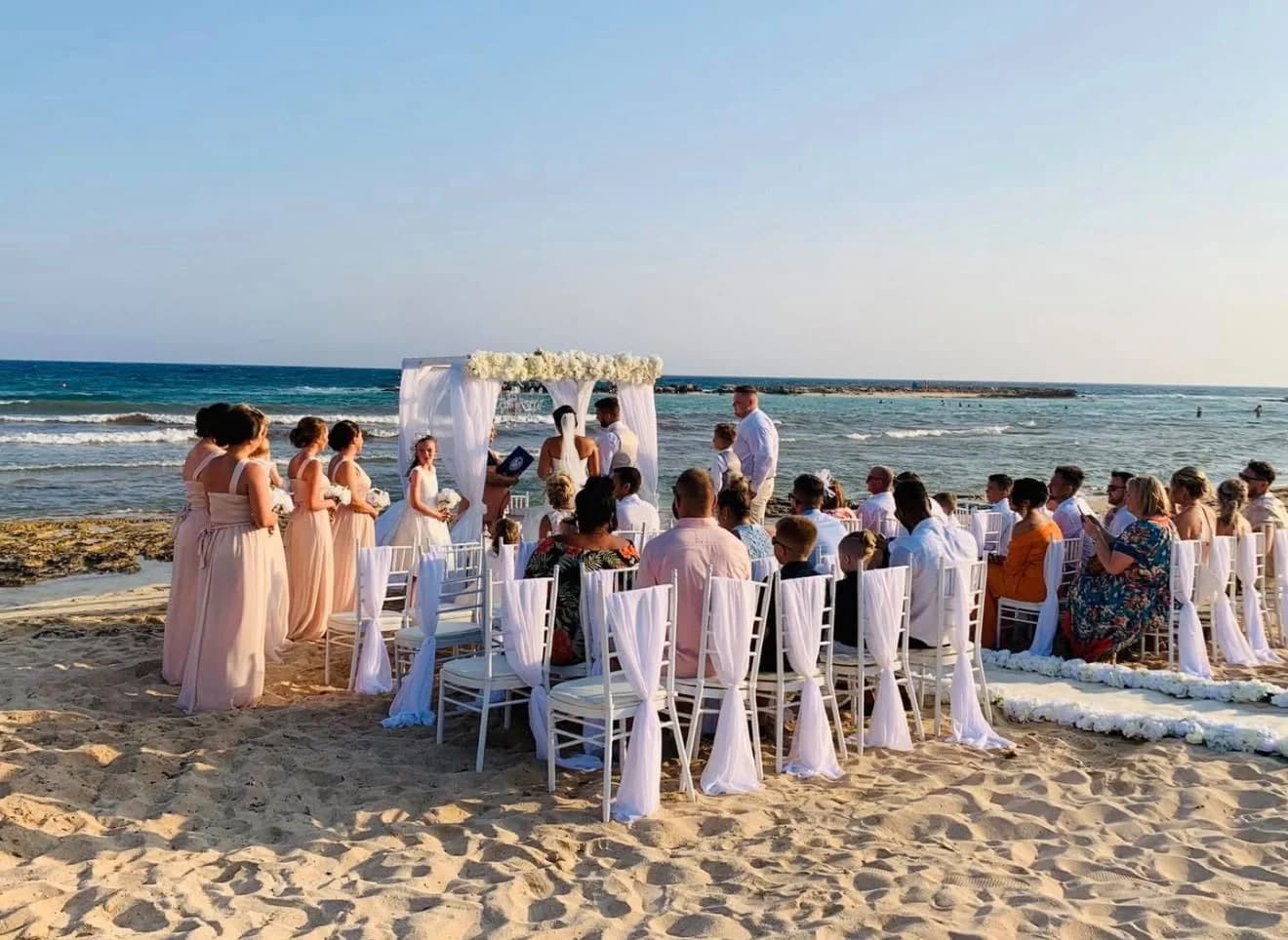 Wedding guests seated for a beach ceremony at Agia Thekla