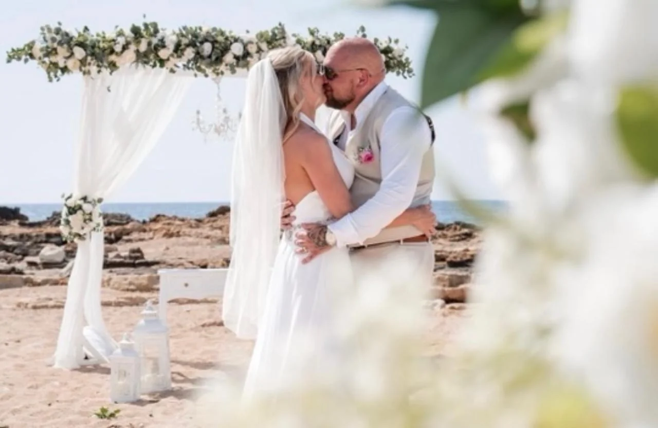 Wedding ceremony beneath a floral arch at Agios Georgios Beach