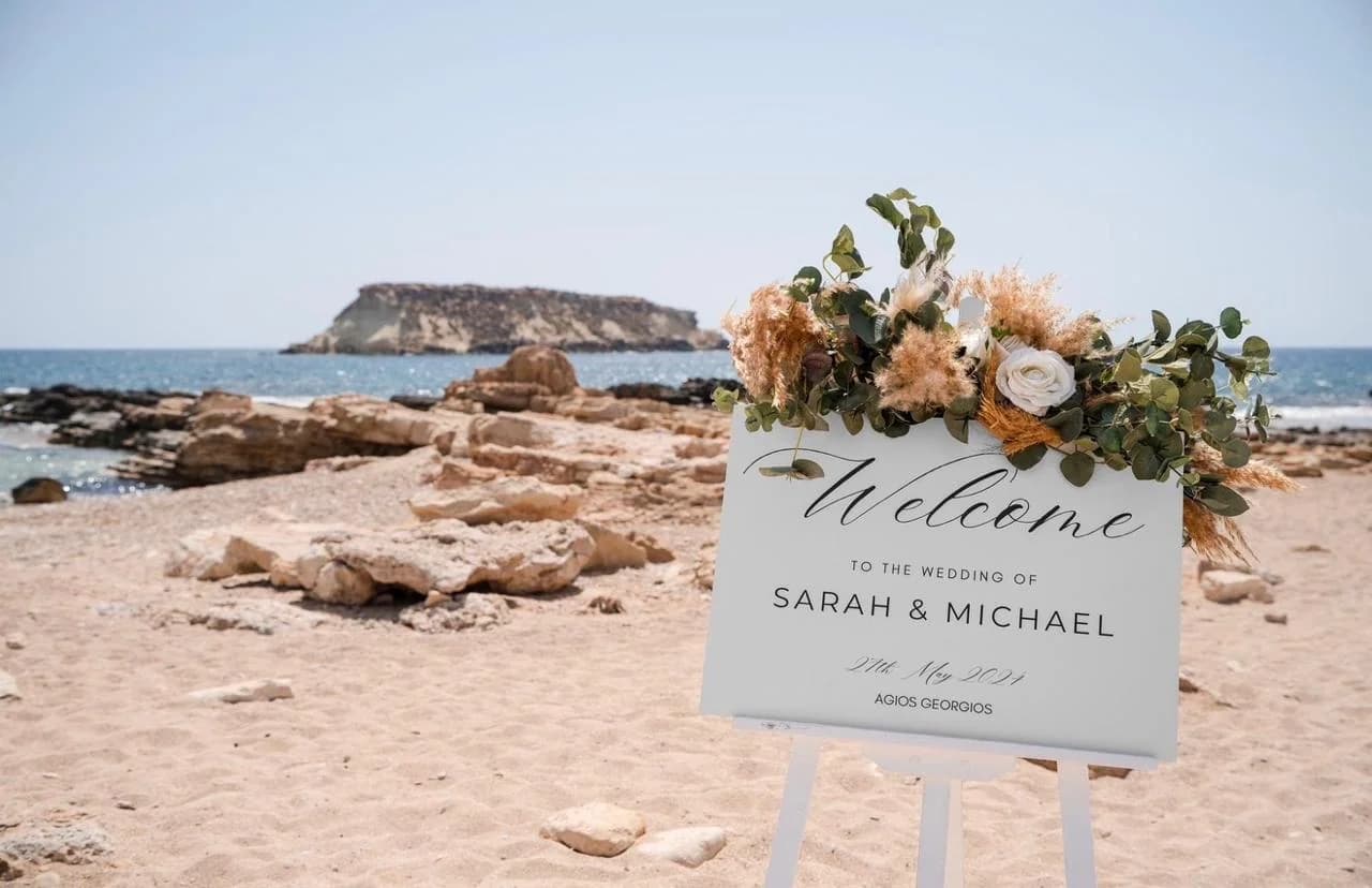 Beach ceremony welcome sign and flowers at Agios Georgios Beach