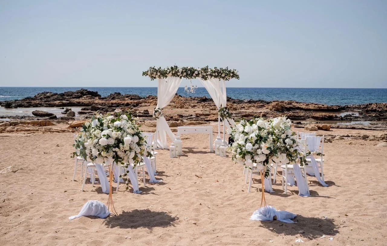 Beach ceremony chairs and floral arch at Agios Georgios Beach