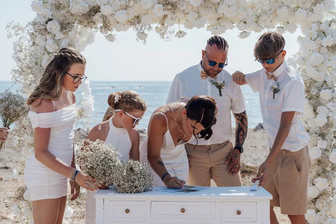 Wedding ceremony beneath a floral arch at Faros Lighthouse Beach