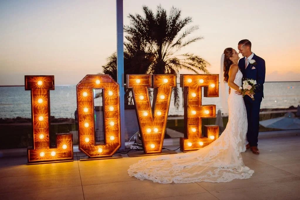 Couple beside illuminated wedding letters at King Evelthon