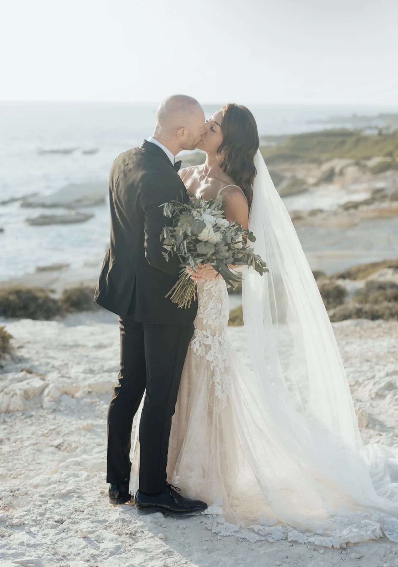 Newlyweds embracing close together beside the water