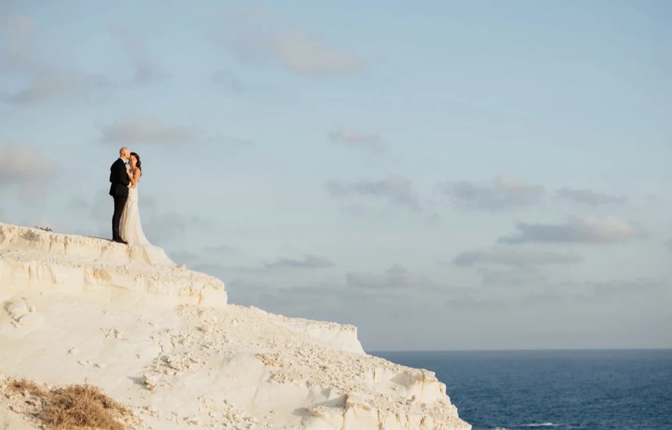 Bride standing on a limestone ledge above the sea